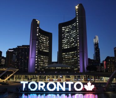 Toronto City Hall stands illuminated against the night sky, showcasing vibrant city lights and iconic architecture.