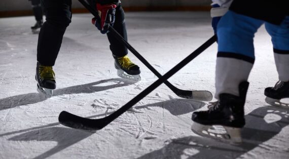 Close-up of hockey players battling for puck during an intense face-off on a lighted ice rink.