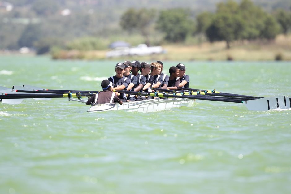 Energetic rowing team practicing on a serene lake during daylight showcasing teamwork and coordination.