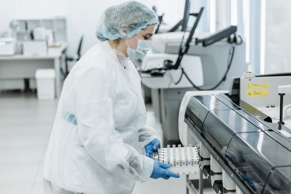 Laboratory scientist in protective gear working with medical samples.