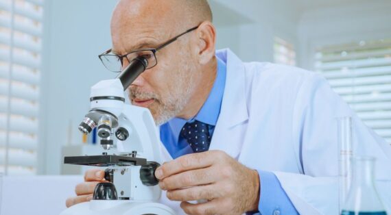 Scientist examining samples through a microscope in a modern laboratory setting.